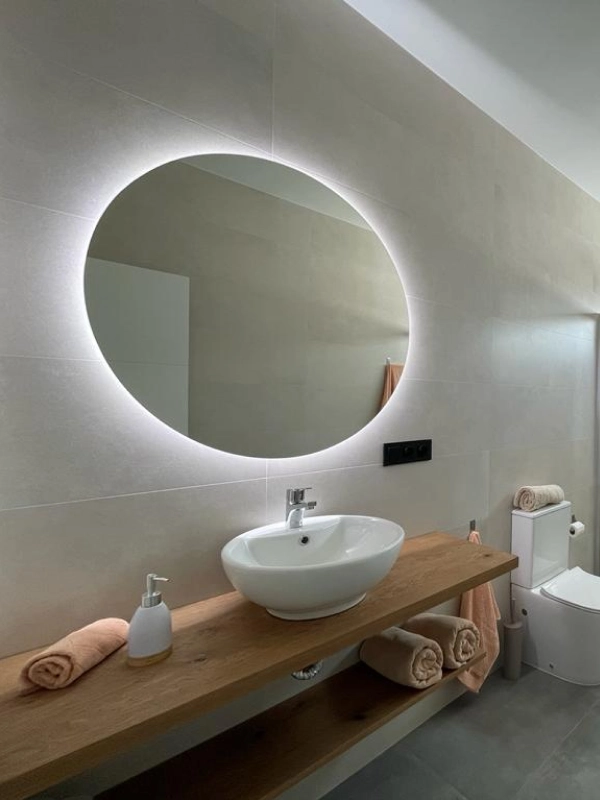 Baño moderno con lavabo y espejo circular iluminado