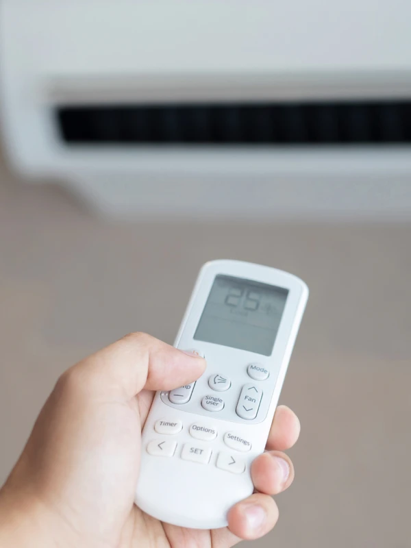 Mano sosteniendo un control remoto de aire acondicionado con pantalla digital