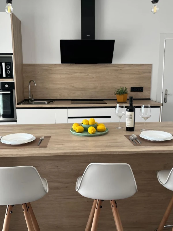 Cocina moderna con comedor integrado, mesa de madera y sillas blancas