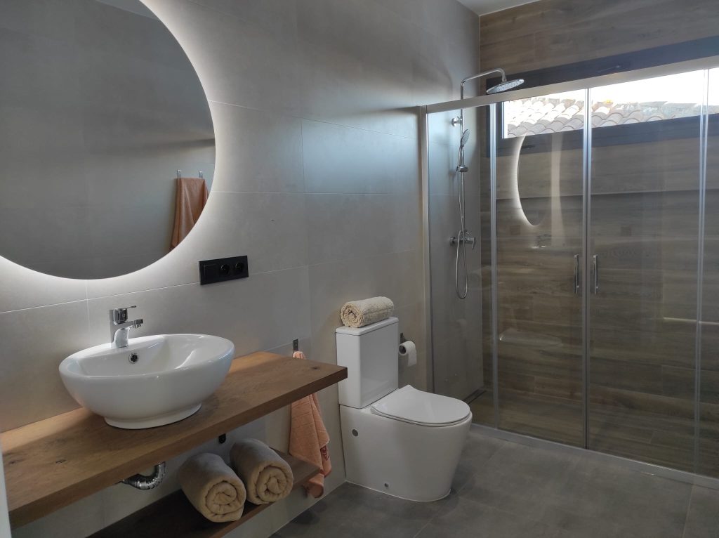 Baño moderno con lavabo de diseño y ducha con mampara de cristal