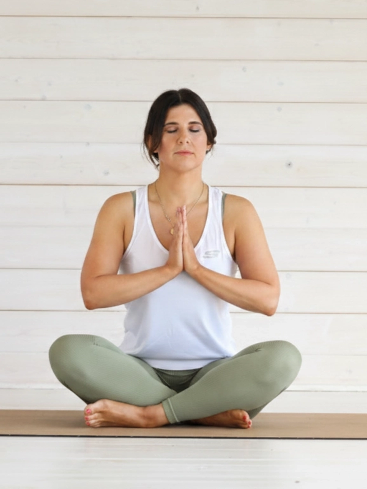 Mujer practicando yoga en una postura de meditación sentada con las manos juntas